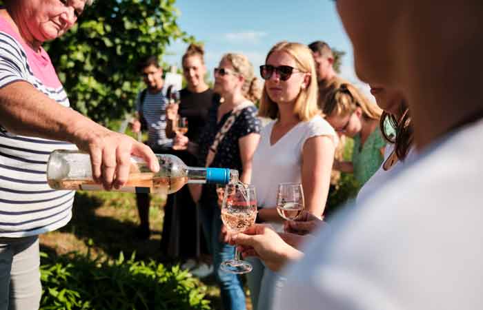 Menschen genießen eine Weinprobe im Freien mit Blick auf die Weinberge in Meersburg am Bodensee.