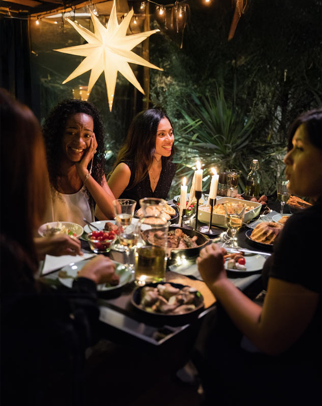 Frauen sitzen an einem weihnachtlich dekorierten Tisch und genießen ein Weihnachtsessen in gemütlicher Atmosphäre.