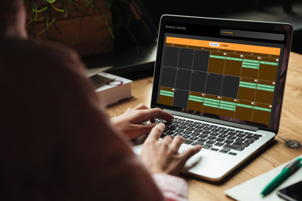 Laptop auf Schreibtisch mit Bildschirm von offenem Buchungskalender der We-Escape Buchungsapp.